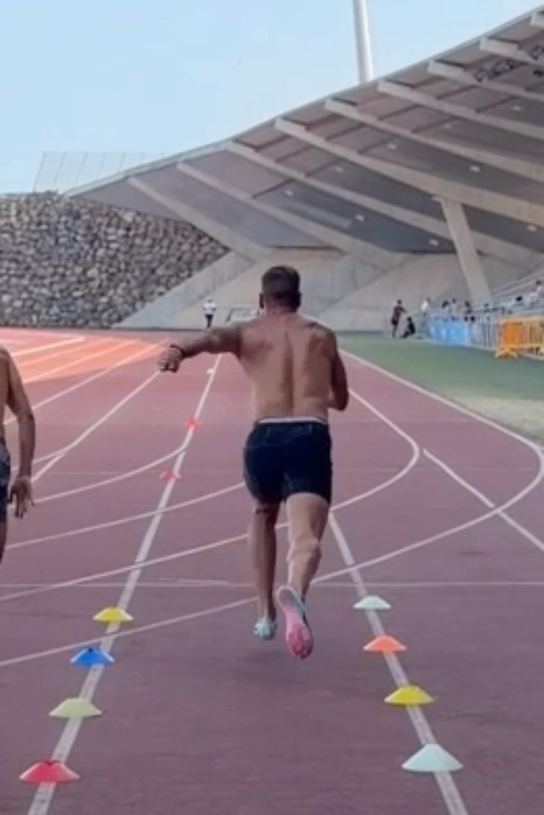 Atleta esprintando a ocho metros de la salida, con el overlay de Banot superpuesto: distancia, cronómetro, velocidad y aceleración instantáneas sobre la curva de velocidad de la carrera